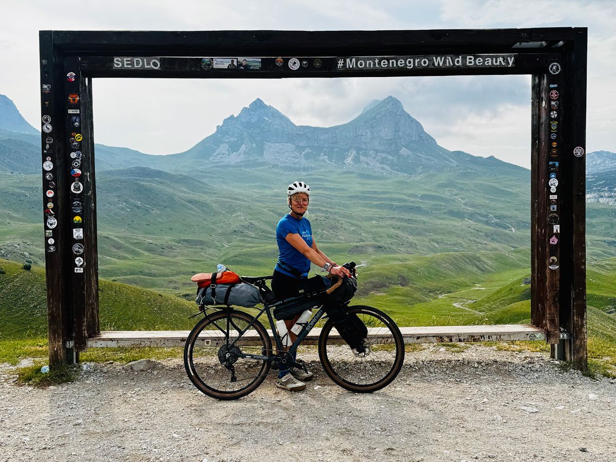 Final image of Chloe and her bike framed by mountains (and a frame)