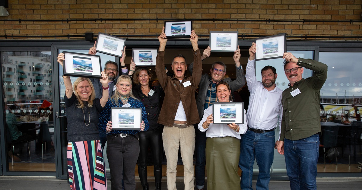 MDHUB kindness award – Read on www.Desbruslais.co.uk – photo by Poppy Berry Last year's winners of MDHUB's awards. They are stood together, holding up their awards, and smiling.